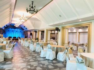 un salón de banquetes con mesas y sillas blancas en Rnana Grand en Phangnga