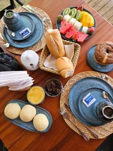 uma mesa de madeira com cestas de pão e pratos de comida em Tawa Caraíva em Caraíva