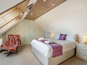 a attic bedroom with a bed and a chair at 3 Bed in St Andrews 54394 in Peat Inn 