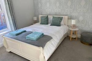 - une chambre avec un lit blanc et des oreillers verts dans l'établissement Tudor House Gloucester by StayStaycations, à Gloucester