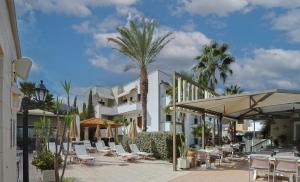 a resort with tables and chairs and palm trees at Bella Elena by Estia in Malia