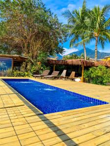 a swimming pool next to a resort with palm trees at Pousada Vila das Velas in Ilhabela