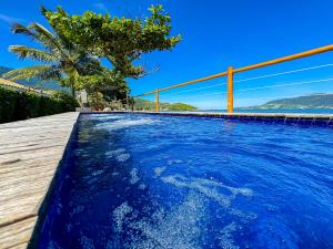 a swimming pool with blue water and a palm tree at Pousada Vila das Velas in Ilhabela