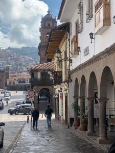 two people walking down a street in a city at Hotel San Pedro Plaza in Cusco