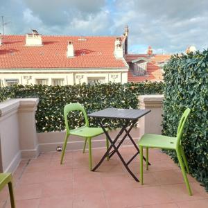 a table and two green chairs on a patio at H33 Hôtel in Nice