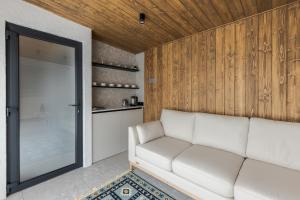 a living room with a white couch and wooden walls at Time ForRest in Maidan Village