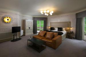 a bedroom with a bed and a couch and a television at Talbooth House & Spa in Dedham