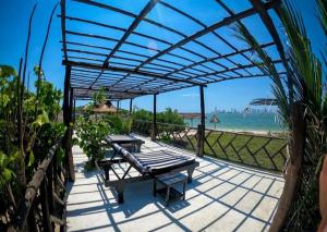eine Terrasse mit einem Tisch und einer Bank unter einer Pergola in der Unterkunft Eco hotel summer beach in Cartagena de Indias