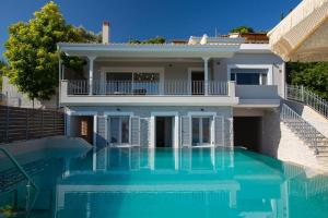 a house with a swimming pool in front of it at Villa Theretro, with superb view in Apolpaina