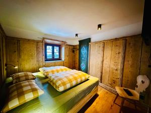 two beds in a room with wooden walls at Chasa Engadina in Sent