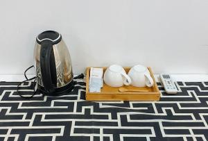 a coffee pot and two mugs on a tray on a floor at Stay Inn Station 1 Boracay by RedDoorz in Boracay