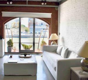 Hermoso departamento en Puerto Madero con vista al río في بوينس آيرس: غرفة معيشة مع أريكة بيضاء ونافذة كبيرة