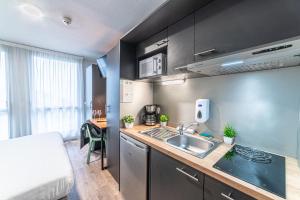 a small kitchen with a sink and a bed in a room at Montempô Bordeaux Centre - Bassins à flot in Bordeaux