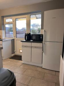 a kitchen with a refrigerator and a microwave at Letzi - Modern 2 Bedroom Apartment Near Heathrow in Hillingdon