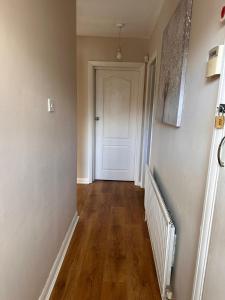 an empty hallway with a white door and wooden floors at Letzi - Modern 2 Bedroom Apartment Near Heathrow in Hillingdon