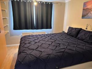 a bedroom with a bed and a black curtain at Letzi - Modern 2 Bedroom Apartment Near Heathrow in Hillingdon