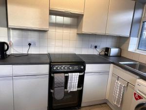a kitchen with a black stove and a sink at Letzi - Modern 2 Bedroom Apartment Near Heathrow in Hillingdon
