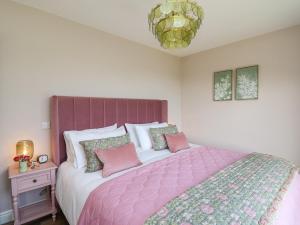 una camera da letto con un grande letto con lenzuola e cuscini rosa di Dol Blodau a Llandrindod Wells