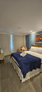 a bedroom with a large bed with a blue blanket at Kitnet Aconchego dos Nobres in Domingos Martins