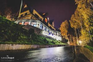 a building on the side of a river at night at Hotel Karolek in Zawoja