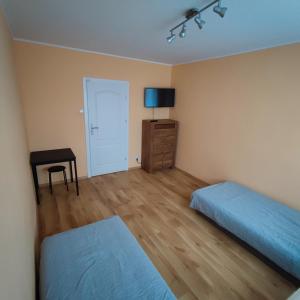 a bedroom with two beds and a dresser and a television at Makuszyńskiego in Gdynia