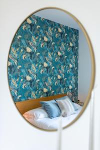 a mirror reflection of a bed with a floral wallpaper at Emilia - Elegant and Modern Apartment in Rome