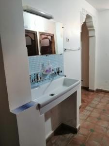 een badkamer met een wastafel en een grote spiegel bij Gite chez Ali Agouti Maison Berbère in Idoukaln