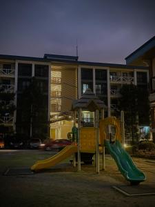 un parque infantil con un tobogán y una sombrilla frente a un edificio en NA Suites at Pine Suites Tagaytay en Tagaytay