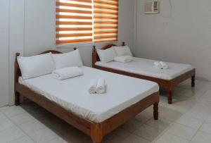 Dos camas en una habitación con toallas. en Langub Beach Resort Sipalay by RedDoorz en Sipalay