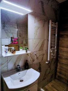 La salle de bains est pourvue d'un lavabo blanc et d'une douche. dans l'établissement Apartman Samsara, à Sarajevo