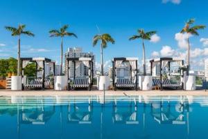 a swimming pool with chairs and palm trees in the background at Luxurious Oceanview 1BR Apt with Resort Amenities in Miami Beach