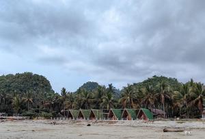 una fila de tiendas de campaña en una playa con palmeras en Langub Beach Resort Sipalay by RedDoorz en Sipalay