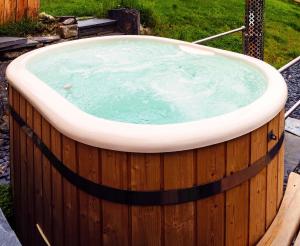 uma banheira de hidromassagem num quintal com cerca de madeira em Snowdonia Hideaway em Tywyn