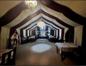 a room with a striped ceiling with tables and a chandelier at Sultan Luxury Camp in Merzouga