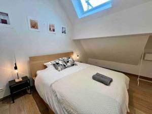 una camera da letto con un grande letto bianco e un lucernario di Le contemporain - Plein centre, place du Marché a Liegi