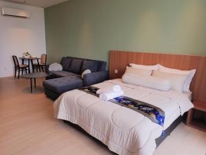 a bedroom with a large bed and a couch at RDHomeStay-RoxyBeachApt in Sematan