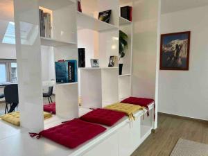 un soggiorno con scaffali bianchi e cuscini rossi di Le contemporain - Plein centre, place du Marché a Liegi