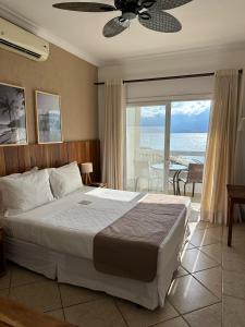 um quarto com uma cama e vista para o oceano em Hotel Mercedes em Ilhabela