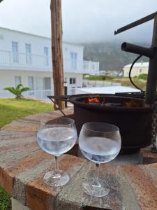 two glasses of water sitting on a table with a grill at Nivenia Beach House in Bettyʼs Bay