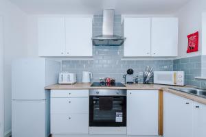 a white kitchen with white cabinets and appliances at Charming Home in Mossley with Free Parking and Wi-Fi Sleeps7 in Mossley