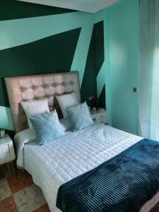 ein Schlafzimmer mit einem großen Bett mit blauen und grünen Wänden in der Unterkunft Villa Pilarin in Orihuela