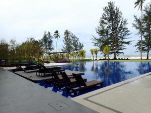 a swimming pool with lounge chairs next to the ocean at RDHomeStay-RoxyBeachApt in Sematan