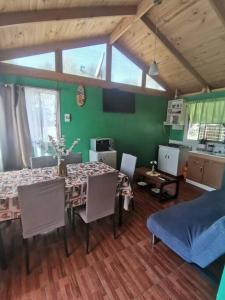 comedor con mesa y pared verde en Cabaña El Quillay, en Linares