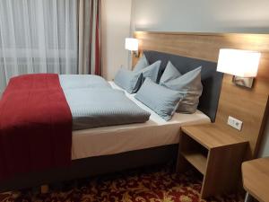 a hotel room with a bed with blue pillows at Landgasthof Hotel Hirsch in Marktlustenau