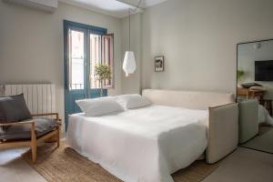 ein Schlafzimmer mit einem großen weißen Bett und einem Stuhl in der Unterkunft SEISSTA Madrid Centro "Remodelado" in Madrid