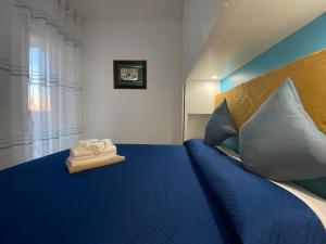 1 dormitorio con 1 cama con sábanas y almohadas azules en Coastal House - Spiaggia e Piscina a dieci passi, en Santa Marinella