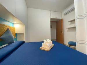 een slaapkamer met een blauw bed en een stapel handdoeken bij Coastal House - Spiaggia e Piscina a dieci passi in Santa Marinella