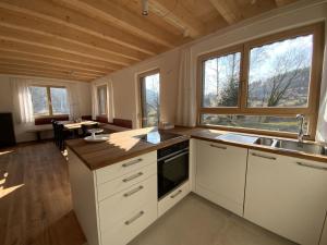 uma cozinha com armários brancos, um lavatório e janelas em Ferienhaus Baiersbronn LUG INS TAL em Baiersbronn