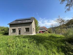 a house with a solar roof on a grassy hill at Ferienhaus Baiersbronn LUG INS TAL in Baiersbronn