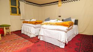 2 camas en una habitación con alfombra roja en Nomad Camp, en Erfoud